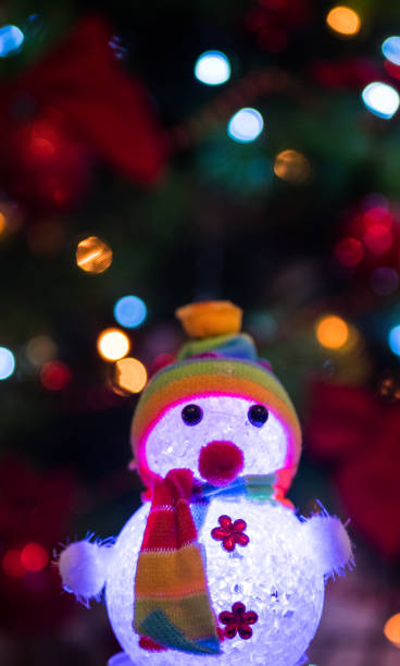 istock glowing snowman on Christmas tree background with garlands 1193758643