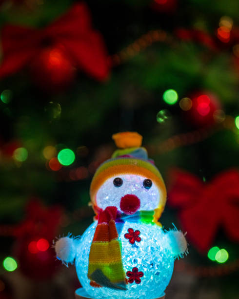 istock glowing snowman on Christmas tree background with garlands 1193758644