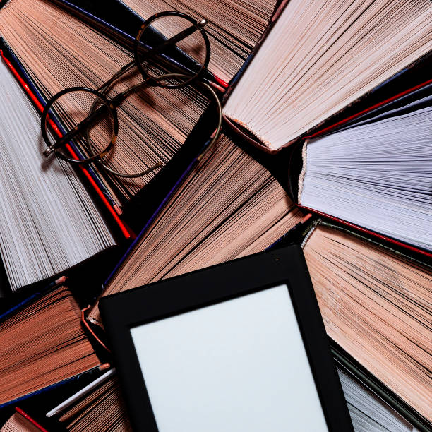 istock The e-book with a white screen lies on the open multi-colored books that lie on a dark background, close-up 1193760773