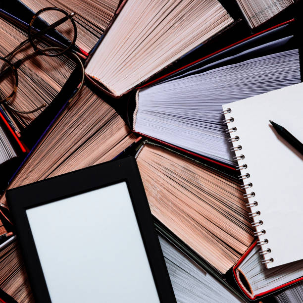 istock The e-book with a white screen lies on the open multi-colored books that lie on a dark background, close-up 1193760789