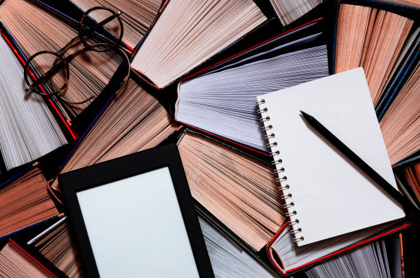 istock The e-book with a white screen lies on the open multi-colored books that lie on a dark background, close-up 1193761014
