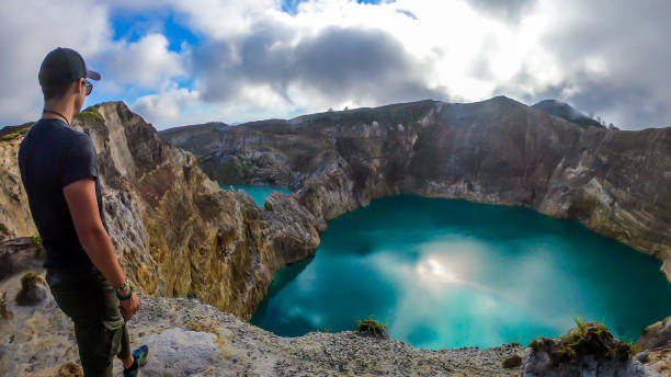 istock Kelimutu - A man admiring turquoise coloured volcanic lakes 1193767752
