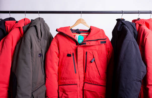 family concept or showroom of down jacket winter parka hanging on a hanger in the wardrobe family concept or showroom of down jacket winter parka hanging on a hanger in the wardrobe coat stock pictures, royalty-free photos & images