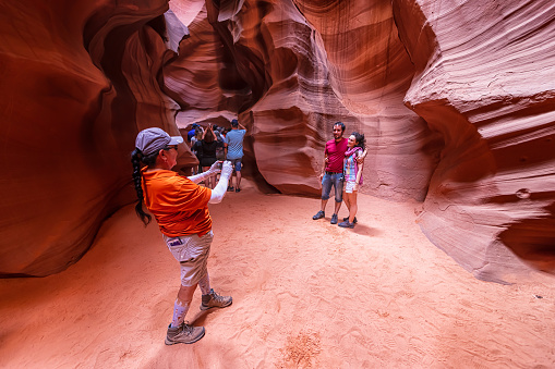 Page, USA - August 10, 2019: Tour group people with guide taking picture with phone inside Upper Antelope slot canyon in Arizona wide angle