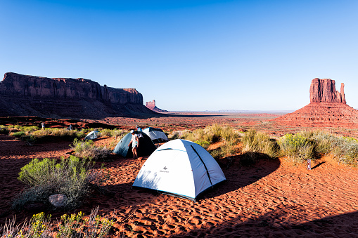 Monument Valley, USA - August 12, 2019: People at the view campground with tents and famous mittens butte mesa formations canyons during sunset in Arizona