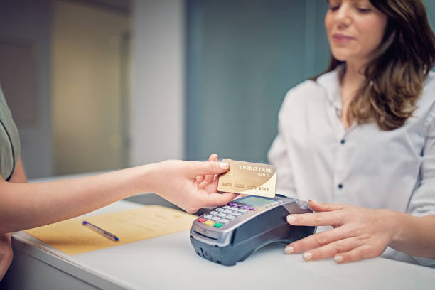 frau zahlt an der rezeption in schönheitsbehandlungsklinik mit kontaktloser kreditkarte - healthcare and medicine receptionist paying credit card stock-fotos und bilder