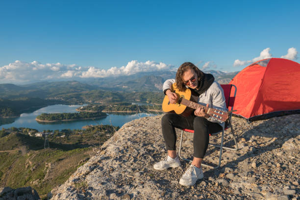 istock Man camping on the mountains singing and playing guitar. 1193773648