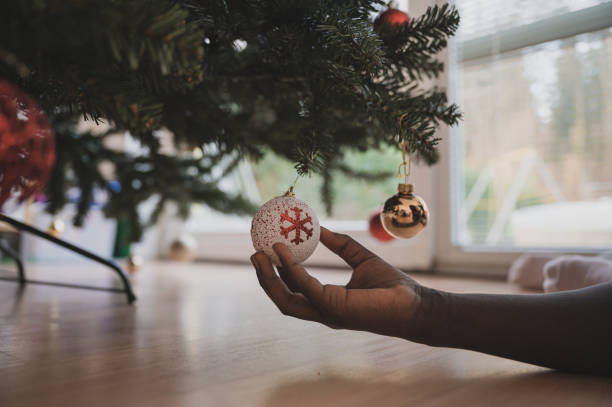 istock Child holding holiday bauble hanging on Christmas tree 1193774243