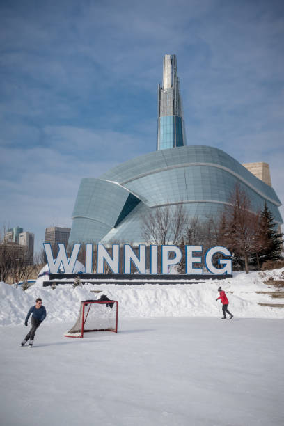 Canadian winter skate Winnipeg MB Canada - February 23rd 2019 : Two make skaters are enjoying the hockey rink at the forks in front of the iconic Winnipeg sign and the Canadian museum for human rights building. winnipeg photos stock pictures, royalty-free photos & images