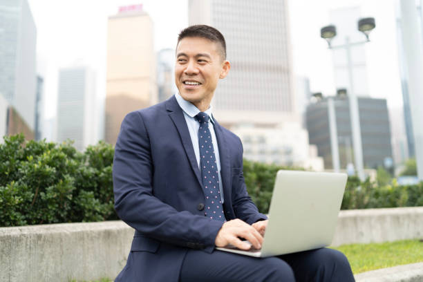 istock Chinese businessman using laptop outdoors, working 1193776060