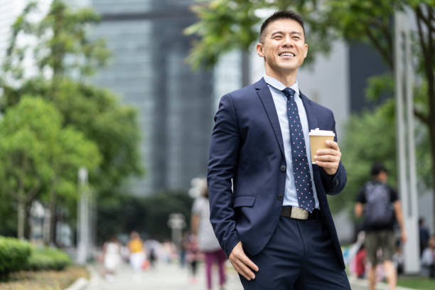 istock Businessman holding coffee cup and documents on street 1193776061