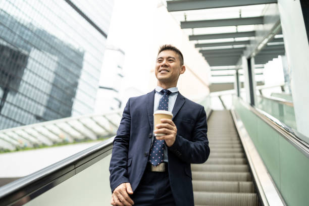 istock Smiling businessman moving down on escalator at workplace 1193776062
