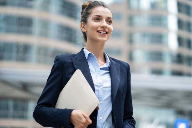istock Smiling woman holding documents and walking on street 1193776066
