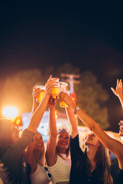 groupe d'amis féminins encourageant avec la bière dans le stationnement d'amusement - music festival park friendship summer photos et images de collection