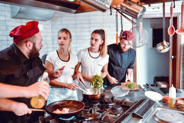 istock Male Chef Instructing Kitchen Team On Frying Meat With Spices 1193789502