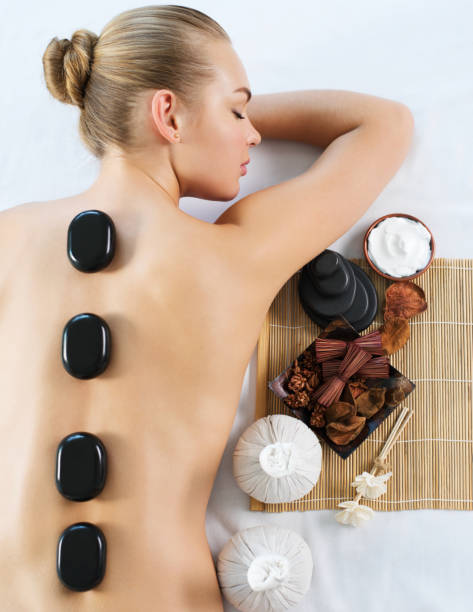 mujer recibiendo masaje de piedra caliente en el salón de spa. - lastone therapy pampering spa treatment women fotografías e imágenes de stock