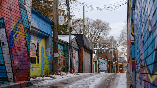 Toronto, Ontario, Canada 12/08/2019. Winter scene of a driveway into a graffiti covered back alley off Dundas St., Toronto, ON. Graffiti covered residential garages.