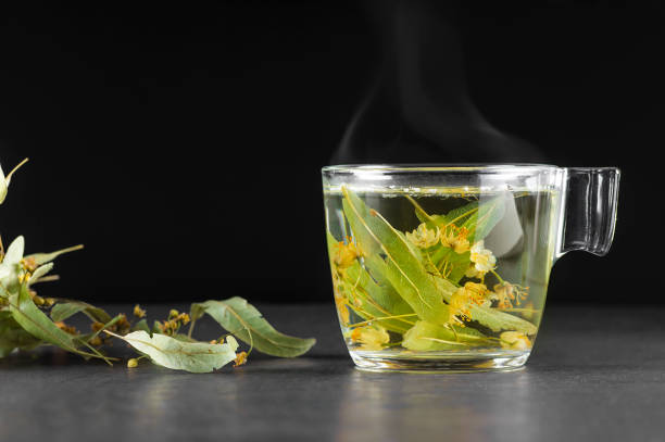 glass cup of linden tea or blooming tilia with linden blossom on rustic table. hot drink winter herbal tea concept, treatment of cold and flu - alternative medicine herb garden plant flower imagens e fotografias de stock