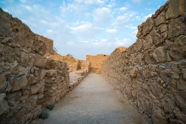 istock Panorama of a path between not high ancient stone walls against the blue cloudy sky. Empty way between the walls of an old middle eastern city. Archeology and excavation findings. Israel, Masada. 1193802112
