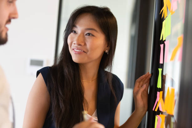 istock Smiling Asian female brainstorm using memo pads in office 1193802305