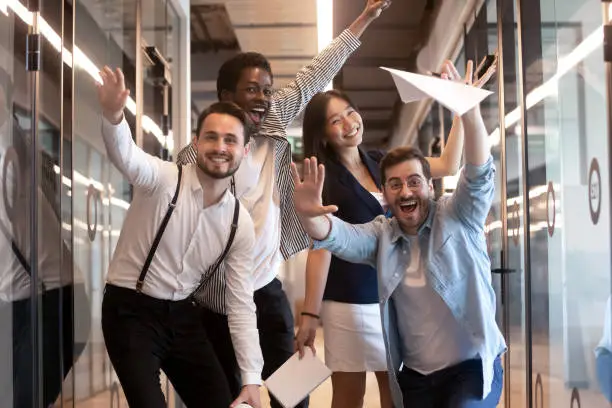 Photo of Funny multiethnic employees posing for picture in office hallway
