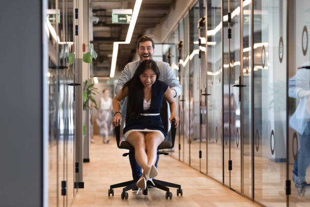 istock Excited multiethnic employees have fun riding chairs in office 1193802352