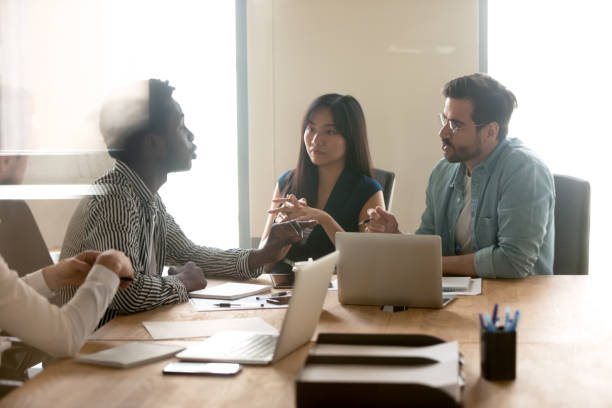 istock Multiracial millennial colleagues discuss ideas at briefing 1193802360