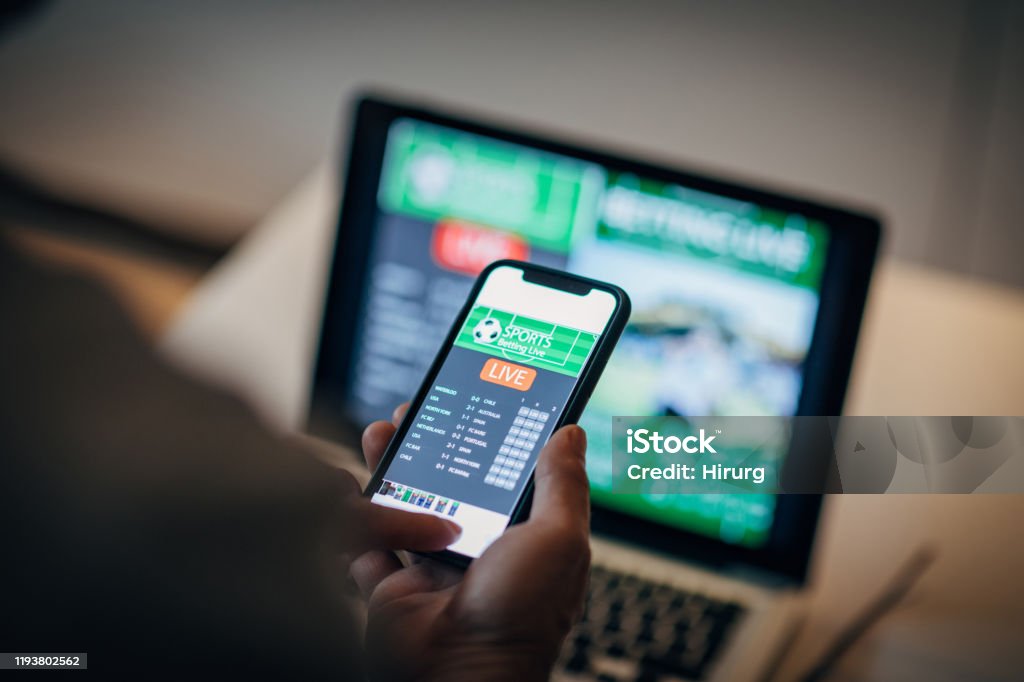 Mature man using mobile app for live betting Mature man using mobile app for live betting and online gambling and watching a sports match Gambling Stock Photo