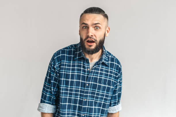 istock Freestyle. Guy in checkered shirt standing isolated on white looking camera surprised 1193802616