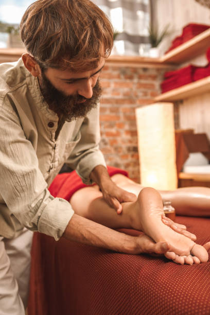 medicina alternativa. terapeuta curando mujer haciendo masaje ayurvédico frotando el pie concentrado - chakra ayurveda recovery herbal medicine fotografías e imágenes de stock