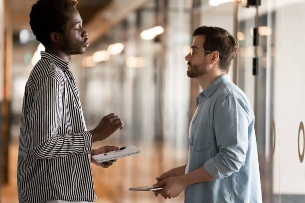 istock Multiethnic male colleagues talk in office hallway 1193807737