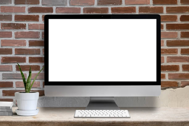 istock Mockup desktop computer white blank screen, houseplant and book on wooden table, blank screen for graphic design. 1193811576