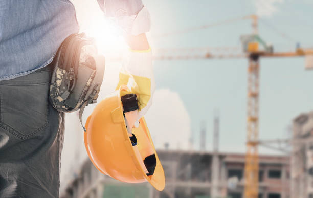 istock Engineer holding yellow helmet standing in front of construction site. 1193811752