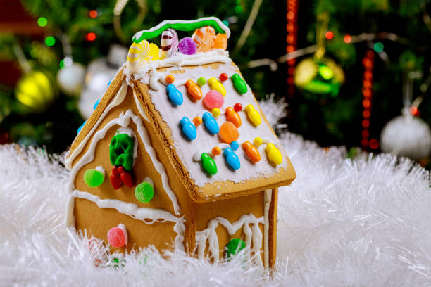 istock Gingerbread house in snow on decorated christmas tree background. 1193815975