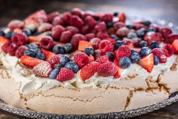 Photo of A traditional Australian desert, Pavlova featuring meringue whipped cream, strawberries, blueberries, raspberries