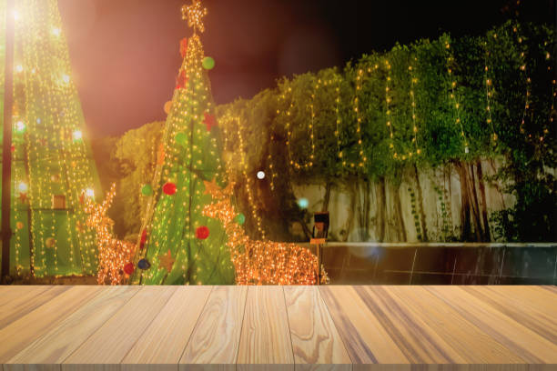 istock Rustic wood table in front of christmas light night,abstract circular bokeh background. Christmas table background. Beautiful xmas gift boxes on floor near fir tree in front lawn. 1193825018
