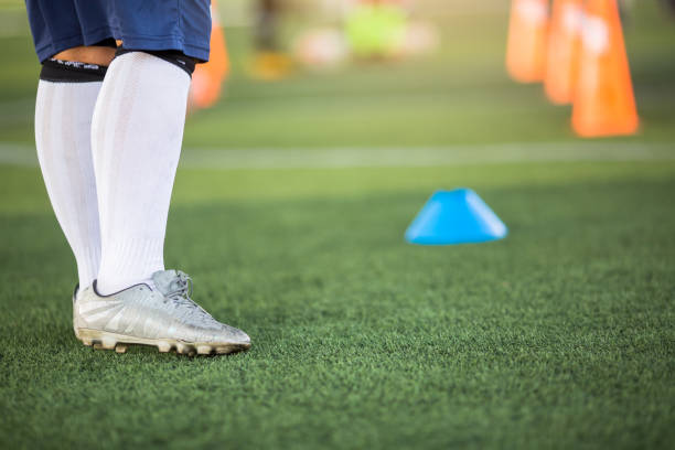 istock Young boy soccer player is standing with blurry marker cones on green artificial turf. 1193825942