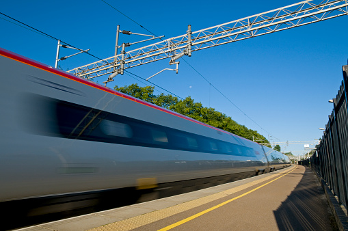 A British high speed passenger train passing through a station in the early morning.