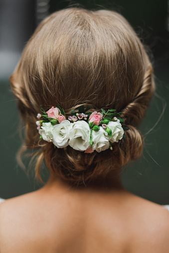 Classic and simple bridal hairstyle with white and pink rose flowers. View of hairdo from behind closeup.
