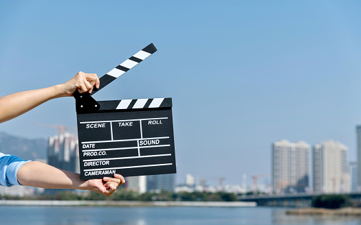 Woman hands holding film slate by the sea.