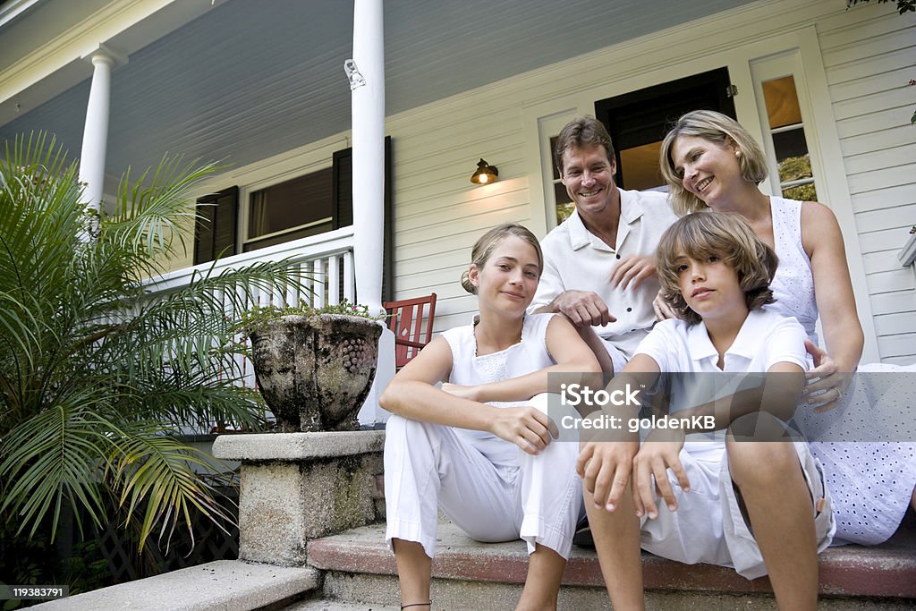 Happy family sitting together on front porch steps  Family Stock Photo