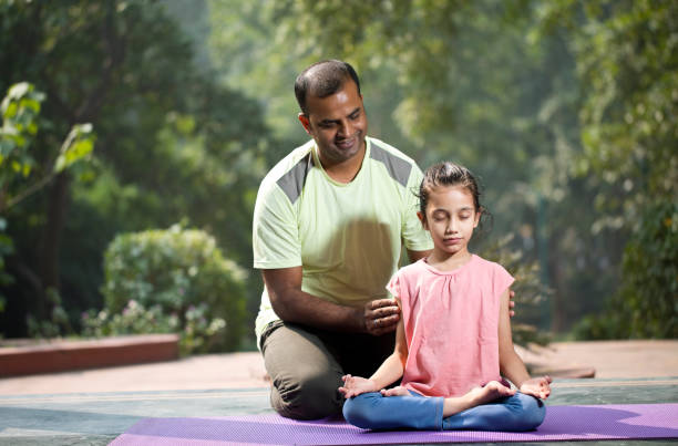 istock Father guiding daughter meditating at park 1193844438