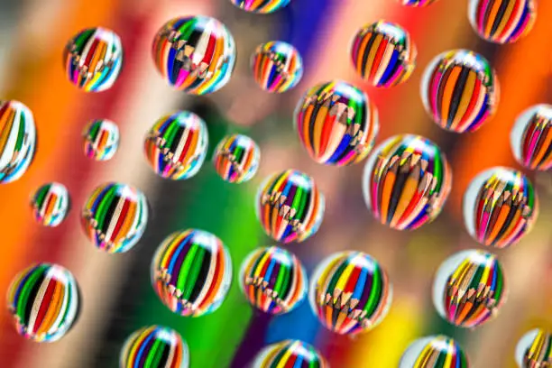 Colored drawing pencils reflected on waterdrops resting a piece of glass