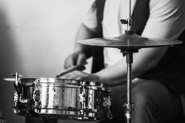 Live music background, drummer plays with drumsticks a drum set. Closeup retro stylized black and white photo