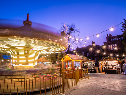 Christmas scene outdoors with a carousel moving in evening lights in  Christmas market of Kingston Upon Thames in London