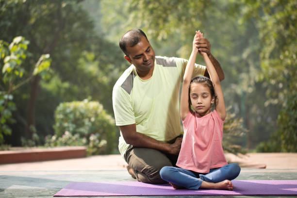 istock Father guiding daughter meditating at park 1193848686