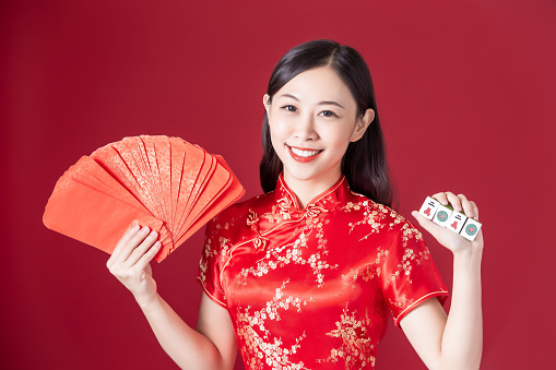 asian woman wearing cheongsam hold red envelopes and Mahjong - chinese word in the image translate 2020 ten thousand
