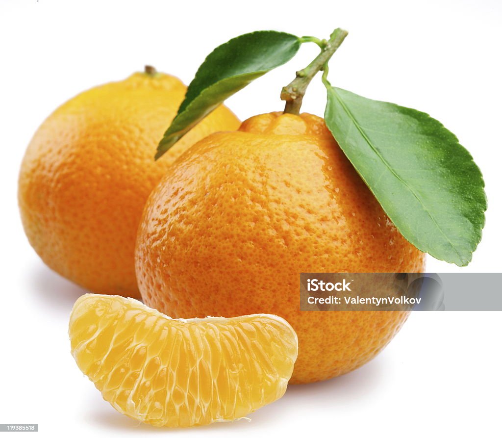 Two ripe tangerines with tangerine wedge on white background Ripe tangerines with leaves and slices on white background. Tangerine Stock Photo