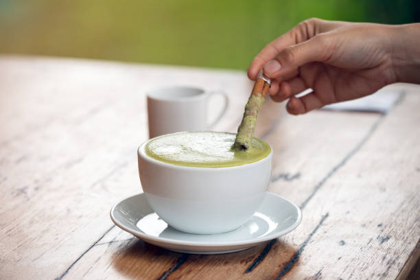 白いセラミックカップのホット抹茶ラテまたは緑茶、シナモンで若い女性の手でソパライザーを着て