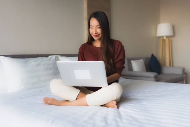 istock Portrait beautiful young asian women using computer and mobile phone on bed 1193870965